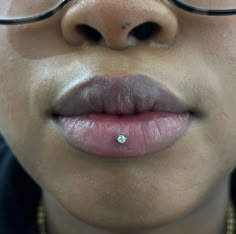 a close up of a woman's lips wearing glasses and a nose ring with a diamond on it