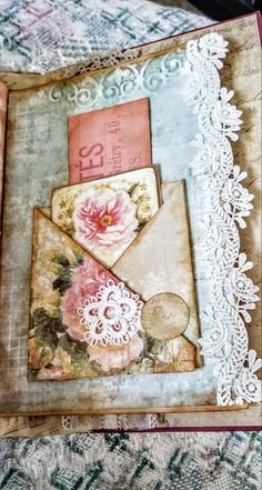 an envelope with flowers and lace on it sitting on top of a doily covered table