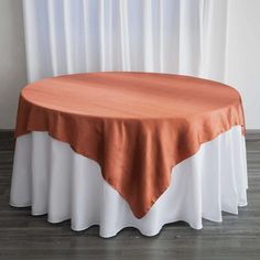 an orange and white table cloth on top of a round table