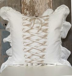 a white pillow with ruffled edges on a chair in front of a wooden wall