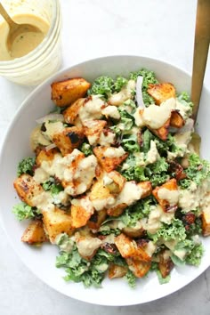 a white bowl filled with salad and dressing next to a jar of mayonnaise