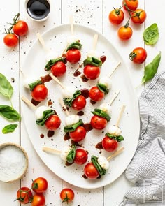 tomatoes and mozzarella skewers on a white plate