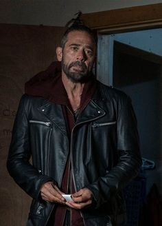 a man in a black leather jacket is looking at the camera