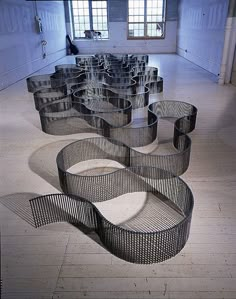 an artistic sculpture made out of metal tubes in a room with white walls and flooring