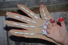 a person holding an object made out of cardboard and string with scissors in their hand