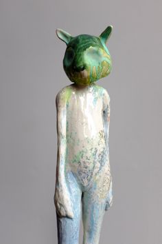 a sculpture of a cat with green and blue paint on it's back legs