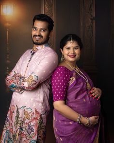 a man and woman standing next to each other in front of a wall with lights