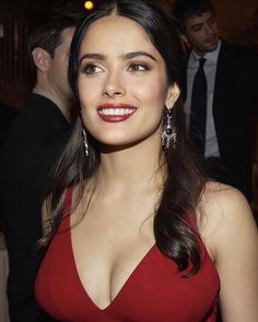 a woman in a red dress smiling at the camera