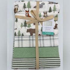 three baby blankets wrapped in green, white and brown with woodland animals on them tied together