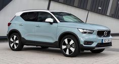 a light blue volvo suv parked in front of a building with black and white accents