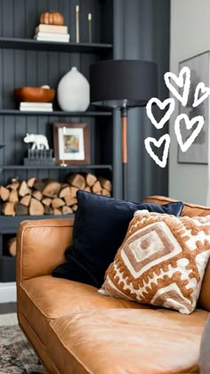 a brown leather couch sitting in front of a book shelf filled with books and pillows