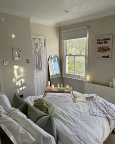 a bed with white sheets and pillows next to a large mirror on the wall above it