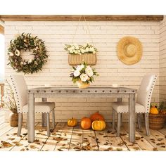 a table and chairs in front of a brick wall with wreaths on the wall