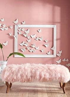 a pink bench in front of a wall with butterflies on it and a white frame