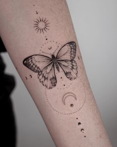 a butterfly tattoo on the arm with stars and crescent moon in the sky above it