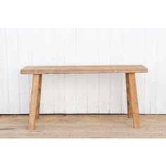 a wooden bench sitting on top of a hard wood floor next to a white wall