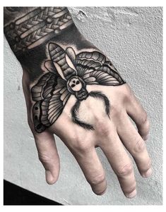 a hand with a black and white tattoo design on the left hand, which has a butterfly