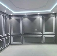 an empty room with gray walls and white paneling on the ceiling is lit by recessed lighting