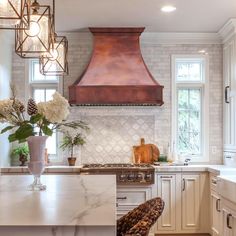 a kitchen with marble counter tops and an oven hood over the stove, surrounded by white cabinets