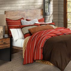 a bed with red and brown comforters in a bedroom