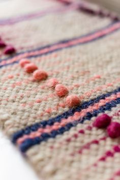 a close up view of a crocheted rug with pom - poms