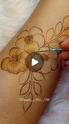 a woman is painting flowers on her leg