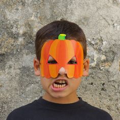 a young boy wearing a paper pumpkin mask