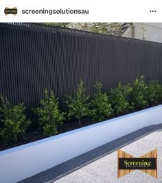 a black fence with white planters in front of it and some green plants on the side