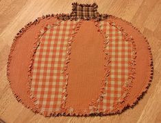 an orange and white checkered pumpkin on a wooden floor with holes in the fabric