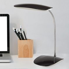 a laptop computer sitting on top of a desk next to a wooden holder with pens and pencils