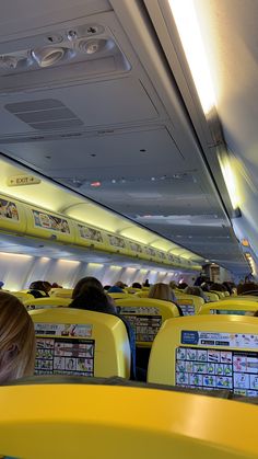 an airplane with people sitting on seats and looking at their laptops in the aisle