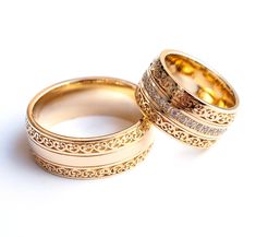 two gold wedding rings with diamond accents on each one, set against a white background