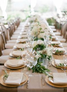 a long table set with place settings and flowers