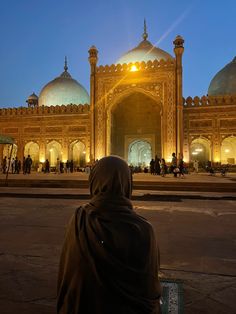 a person sitting on a bench in front of a large building with many arches and domes