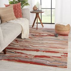 a living room area with a couch, rug and coffee table in front of a window