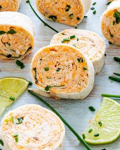 several burritos are arranged on a table with lime wedges