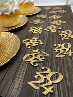 some cupcakes are sitting on top of a table with gold numbers and frosting