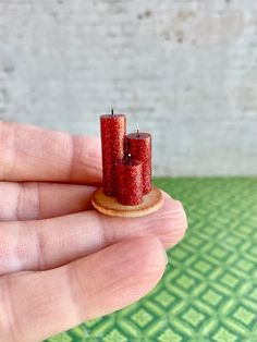 a small red candle sitting on top of a piece of wood in someone's hand