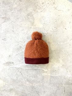 The Hat:Mohair rich and featuring an lovely subtle texture, this hat is designed for warmth! This beanie is also wonderfully soft and fluffy- the edge is knitted from soft lambswool in a contrasting colour for a warm soft finish and topped with a mohair pom pom. This hat is available in three colour combinations; orange and burgundy, taupe and brown, grey and charcoal. The Materials:The beanie is made from a beautiful, luxurious mohair rich yarn; 30% mohair 40% acrylic 30% nylon. The pompoms are Mohair Beanie, Mohair Hat, Fluffy Hat, Navy Beanie, Three Color Combinations, Fox Hat, Red Beanie, Blue Beanie, Hat Wool