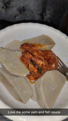 a white plate topped with ravioli and sauce next to a fork on top of a table