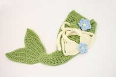 a crocheted mermaid tail with blue and white flowers on it, laying down