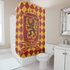 a red and yellow shower curtain with a rampant crest on it in a white bathroom