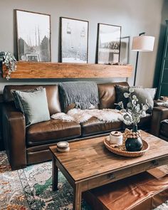 a living room with couches, tables and pictures on the wall above them in front of a window