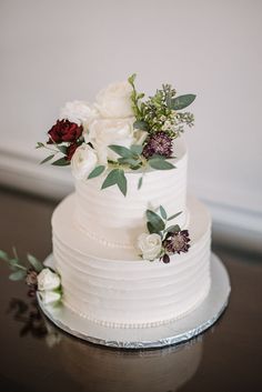 a white wedding cake with flowers and greenery