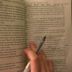 a person holding a pen and looking at an open book with writing on the pages