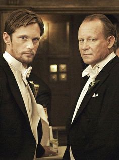 two men in tuxedos standing next to each other looking at something off camera