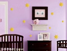 a baby's room with purple walls and yellow stars on the wall