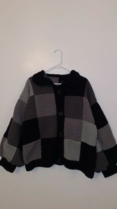 a black and grey sweater hanging on a white wall