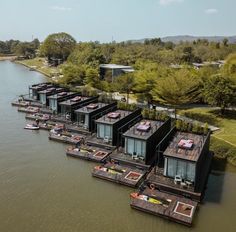 several floating houses on the water with trees in the background