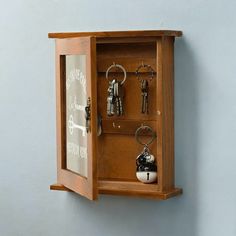 a wooden case with keys and keychains in it hanging on the side of a wall